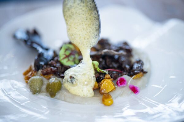 Dressage gastronomique avec émulsion, baies et fleurs comestibles en haute cuisine